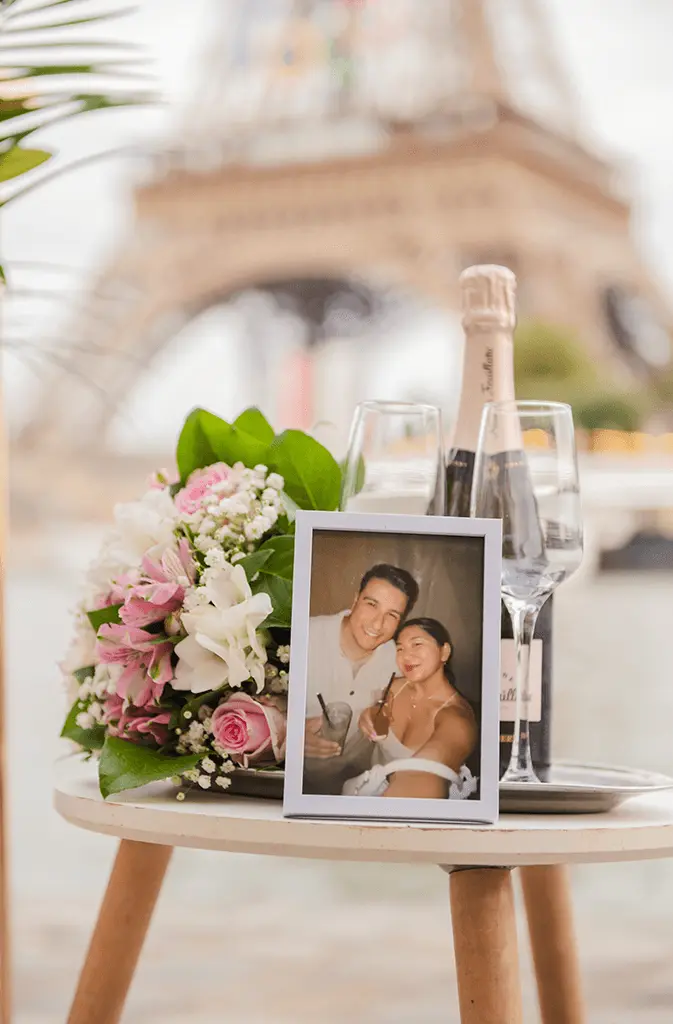 Table with photo frame flowers glasses bottle